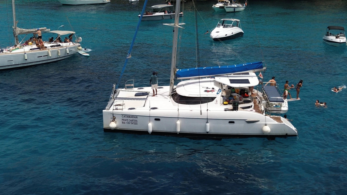 Catamarano a vela all'ancora con persone che fanno il bagno intorno