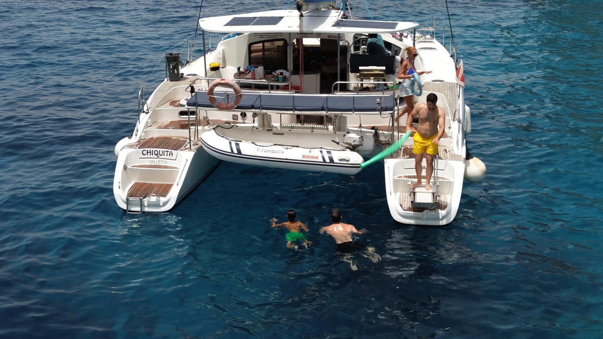 Bagno in mare a poppa del catamarano a vela