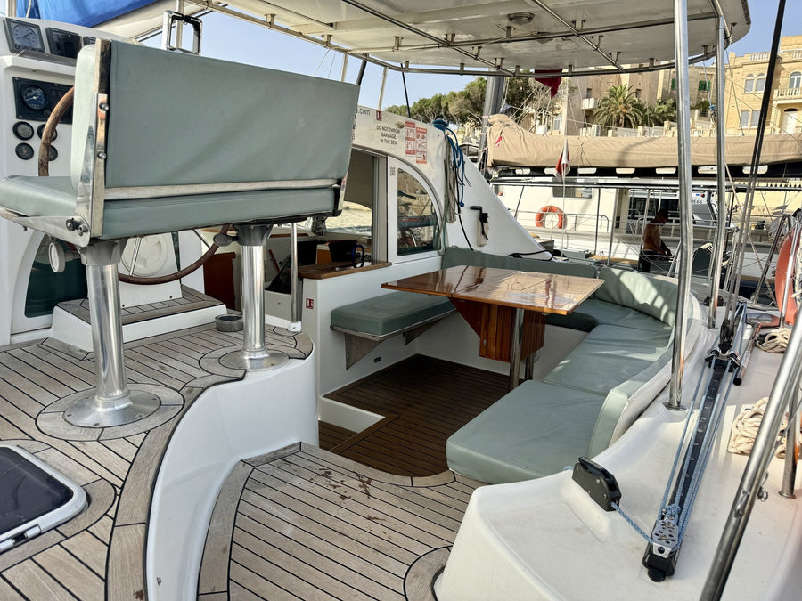 Schattiges Cockpit des Katamarans mit Tisch und Sitzbänken